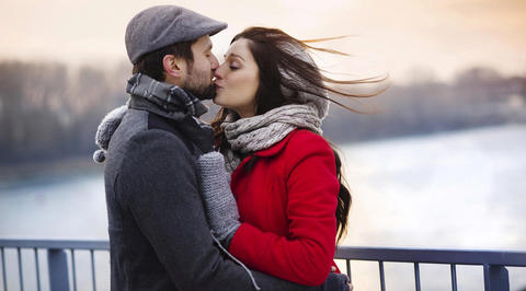 Man and woman kissing on bridge in winter