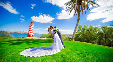 Man and woman kissing in front of red and white striped lighthouse