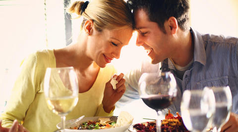 Man and woman touching foreheads while eating dinner together