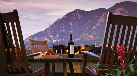 2 glasses of red wine and cheeseboard with mountains in background
