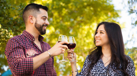 Man and woman raising glasses of red wine